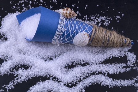 Sea salt in a blue paper bag is scattered on a black background. Sol Ornamental package.の写真素材