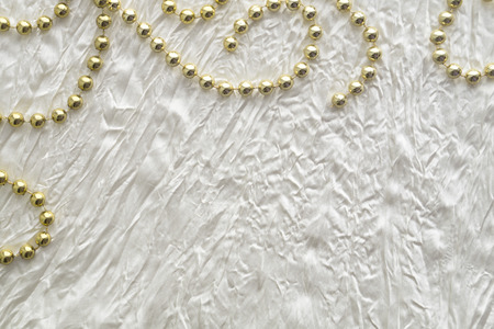 Wedding or celebration background with golden beads and white silkの写真素材