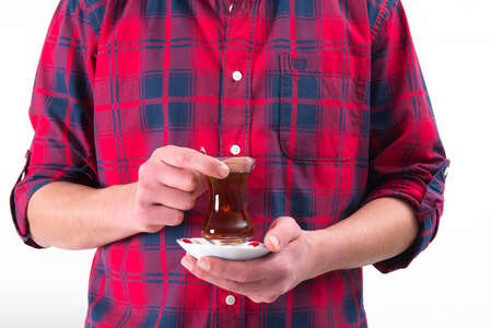 Man in red shirt is holding Turkish tea glass in his handの写真素材