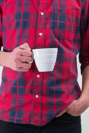 Man in a red shirt is holding a white coffee mug in his hand.の写真素材