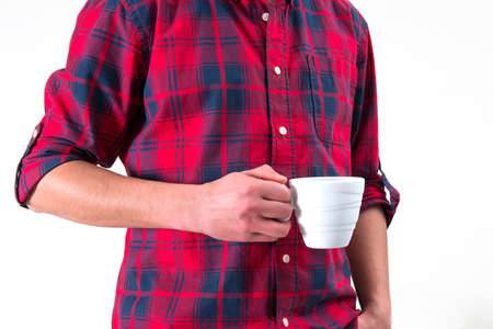 Man in a red shirt is holding a white coffee mug in his hand.の写真素材