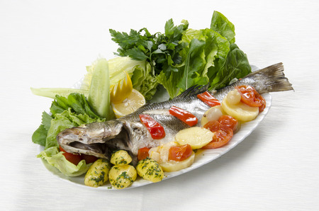 Grilled sea bass with vegetables on a white backgroundの写真素材