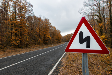 traffic sign on the forest road in the autumnの写真素材