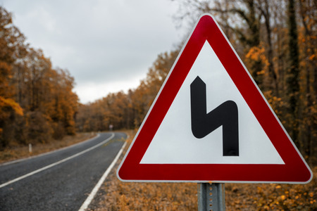 traffic sign on the forest road in the autumnの写真素材