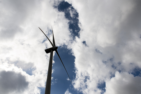 Dark silhouette of a windmill on blue sky with white cloudsの写真素材