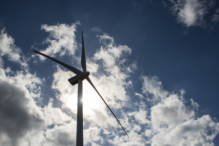Dark silhouette of a windmill on blue sky with white cloudsの写真素材