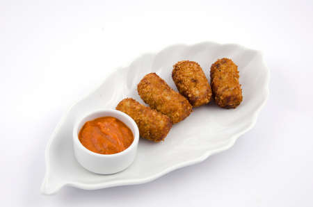 Potato croquettes and sauce on a white serving plateの写真素材