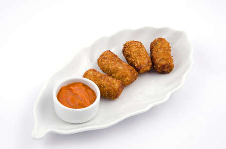 Potato croquettes and sauce on a white serving plateの写真素材