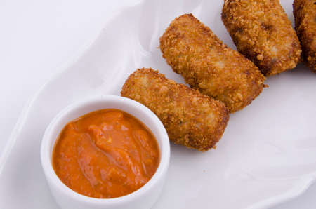 Potato croquettes and sauce on a white serving plateの写真素材