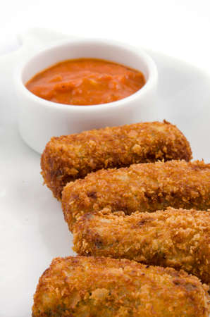 Potato croquettes and sauce on a white serving plateの写真素材