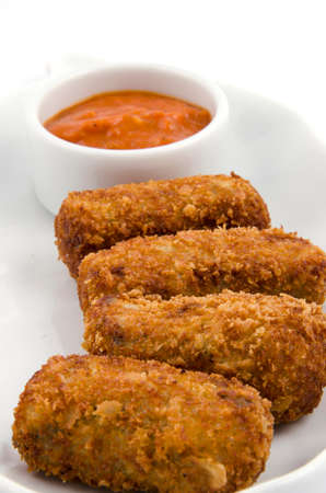 Potato croquettes and sauce on a white serving plateの写真素材