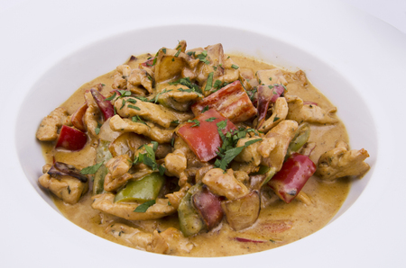 curry sauce on the plate of chicken with vegetables on a white backgroundの写真素材