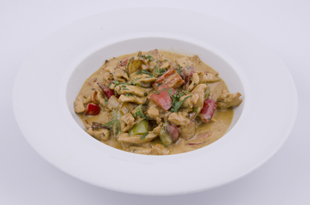 curry sauce on the plate of chicken with vegetables on a white backgroundの写真素材