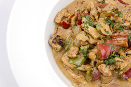 curry sauce on the plate of chicken with vegetables on a white backgroundの写真素材