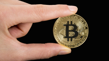 man's hand holding golden Bitcoin on black backgroundの写真素材