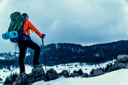backpacker camper man walking in mountains in winterの写真素材