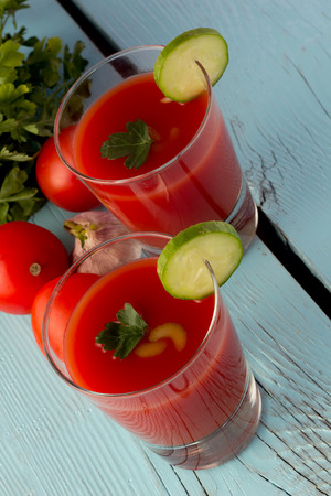 Shot of tomato gazpacho in glasses over blue wooden table verticalの写真素材