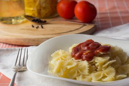 Farfalle pasta with tomato sauce on white dishの写真素材