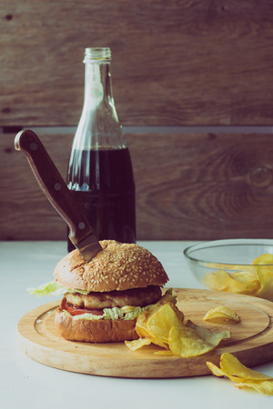 Knife in burger, cola and chips  vertical selective focusの写真素材