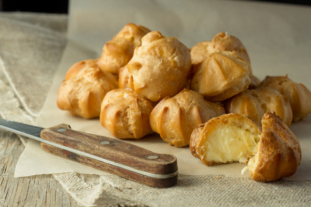 Cream puffs on cooking paper and knife selective focusの写真素材
