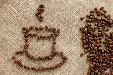 Cup of coffee beans on linen top view selective focus