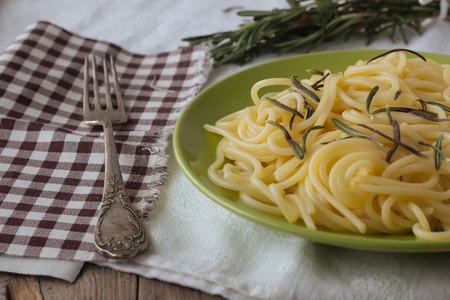 Plate of spaghetti with rosemary and old metal fork selective focusの写真素材