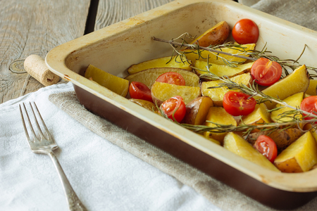 Pan with baked potatoes and cherry tomatoes selective focusの写真素材