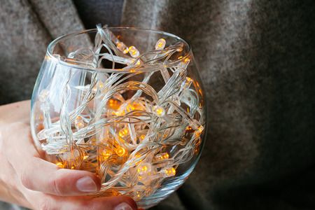 Hand holding glass with fairy lights selective focusの写真素材