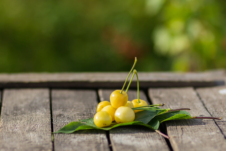 An image of yellow cherries on a wooden tableの写真素材