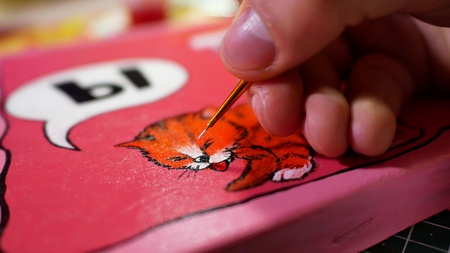 Man in the process of drawing with acrylic paints picture with catの写真素材