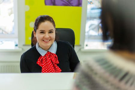 Beautiful smiling woman sitting on the reception in beauty salon.の写真素材