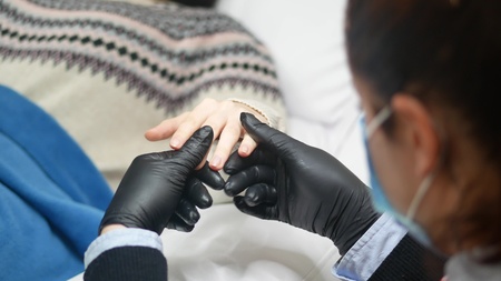 Closeup shot of a woman in a nail salon receiving a manicure by a beautician with nail file.の写真素材