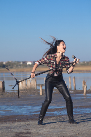 Rock musician woman singing near water outsideの写真素材