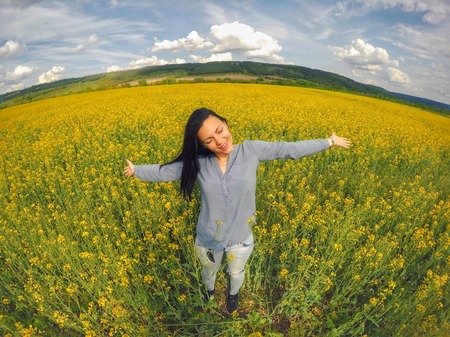 Emotional portrait of young beautiful woman in rapeseed fieldの写真素材