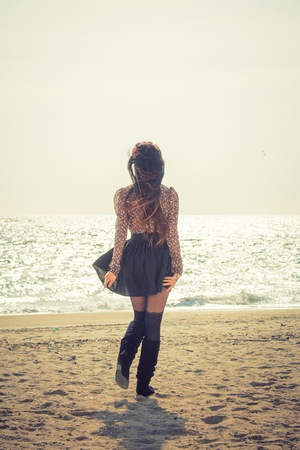 Portrait of young beautiful trendy woman standing on the sea or ocean beachの写真素材