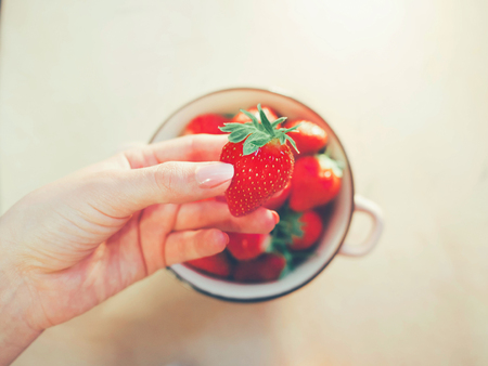 strawberry bowl in hands of woman wearing gray warm sweater, selective focus. Clean eating, healthy, vegetarian, dieting food conceptの写真素材