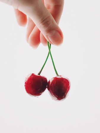 cherries in the womens hand isolated on white backgroundの写真素材