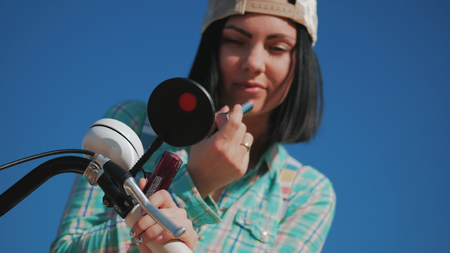 Woman is painting lipstick, woman with lipstick, woman is looking in bicycle mirrorの写真素材