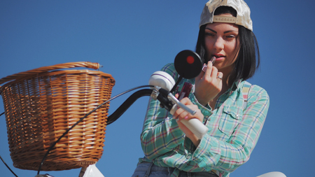 Woman is painting lipstick, woman with lipstick, woman is looking in bicycle mirrorの写真素材