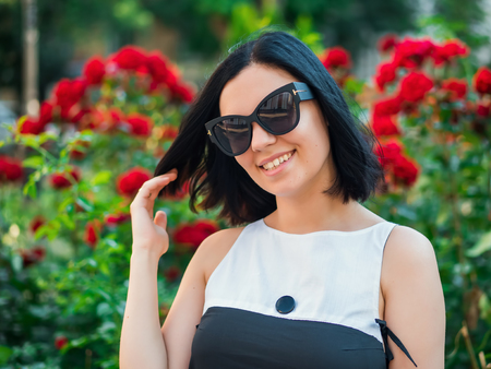 Beautiful young woman on a background of red flowers. The concept of beauty and health. Beautiful fashion girl, sweet and sensual.の写真素材