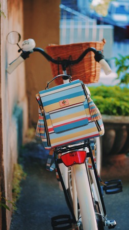 Beautiful stripes backpack on retro white bicycle in the street. Trendy hipster background.の写真素材