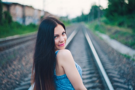 Young sexy girl teenager with long hair in jeans on a railway.の写真素材