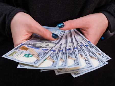 Woman hand with dollars isolated on black background. Girl counting money.の写真素材