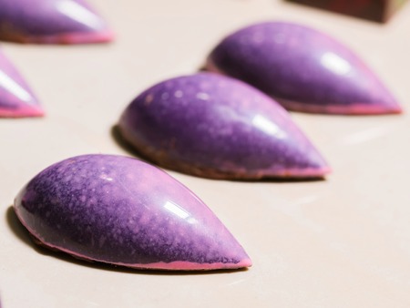 Set of colorful luxury handmade violet bonbons on white background. Exclusive handcrafted chocolate candies. Product concept for chocolatierの写真素材