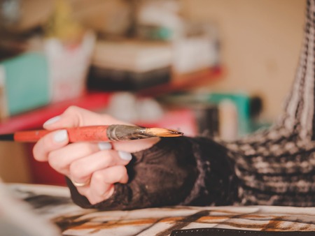 Female artists hand holding big brush. Woman painting picture.の写真素材