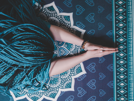 Concentrated woman with blue african braids praying with wooden rosary mala beads. Namaste. Close up...