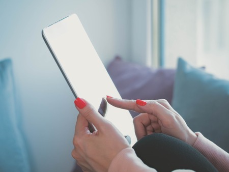 Hands of woman using tablet computer touchscreen at her cozy home. Female hands with digital map-case in bed. Technology, education conceptの写真素材