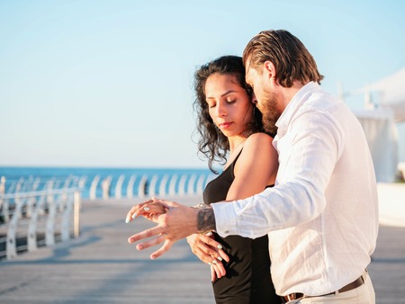 Portrait of young attractive couple dancing latin bachata near sea. Dance performed by a...