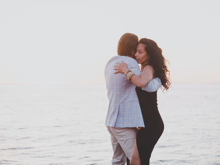 Young spanish couple against sunset sea background. Small resort european city. Man and woman...