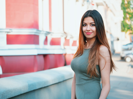 Portrait of young attractive girl looks into the camera with smile. Woman with oriental face, brown eyes and stylish ombre dyed long haistyle on architecture background. Street style.の写真素材